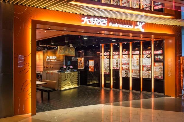 大快活分店門面照片：橙色招牌顯示大快活Fairwood，門前有餐牌展示架